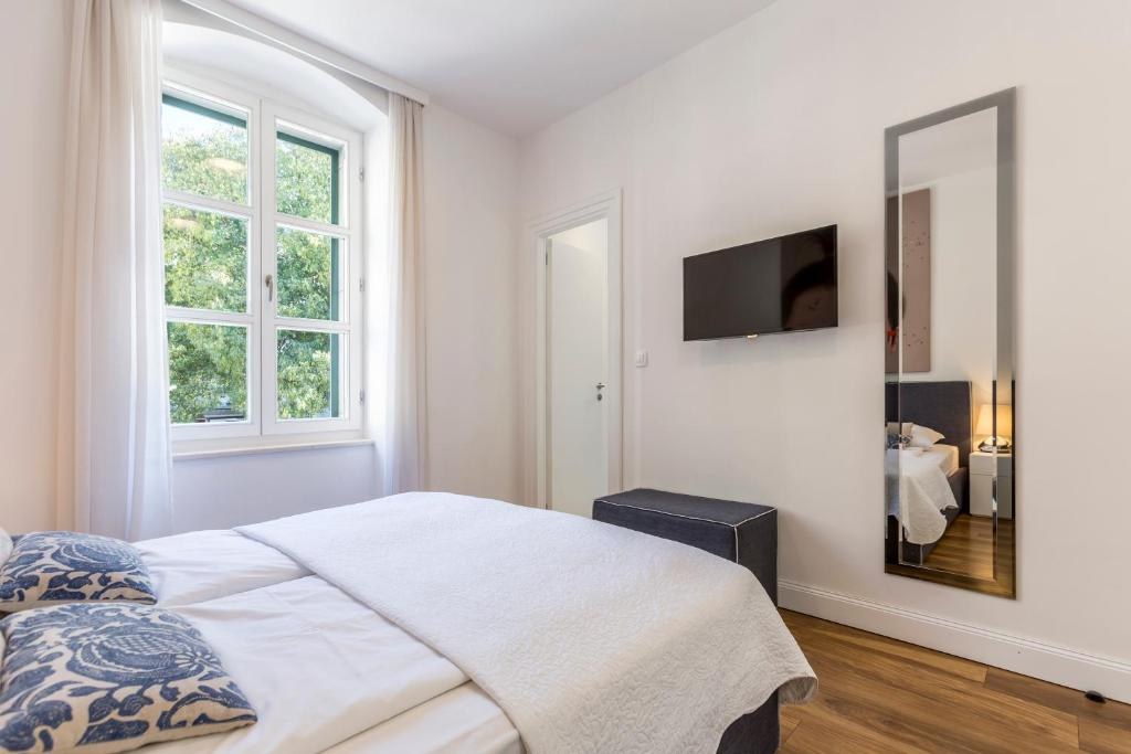 White bedroom with a mirror at Piano Nobile Rooms in Split